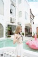 A woman standing next to a pool with a pink flamingo float.