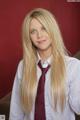 A woman with long blonde hair wearing a white shirt and red tie.