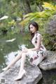 A woman sitting on a rock by a pond.