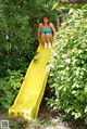 A woman sitting on a yellow slide in the woods.