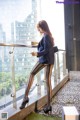 A woman in black tights and high heels standing on a balcony.