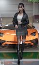 A woman standing in front of an orange sports car.