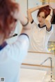 A woman brushing her hair in front of a mirror.