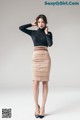 A woman in a black top and a beige skirt.