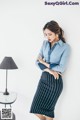 A woman leaning against a wall with her arms crossed.