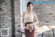 A woman standing in front of a brick wall holding a purse.