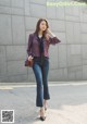 A woman walking down the street wearing a red blouse and jeans.