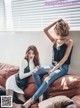 two women sitting on top of a brown couch