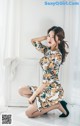 A woman in a floral dress sitting on the floor.