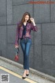 A woman in a blue blouse and jeans is walking down the street.