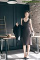 A woman in a black dress standing in front of a table.