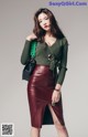 A woman in a green sweater and a red leather skirt.