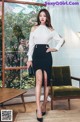 A woman in a white blouse and black skirt posing for a picture.