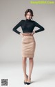 A woman in a black top and a beige skirt.