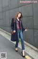 A woman is walking down the street wearing a blue coat.