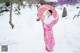 A woman in a pink kimono holding an umbrella in the snow.