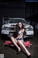 A woman sitting on top of a car in a garage.