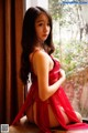 A woman in a red lingerie sitting on a window sill.