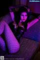 A woman in fishnet stockings sitting on a couch.