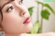 A close up of a woman's face with a plant in the background.