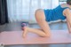 A woman in a blue tank top is doing a yoga pose.