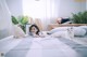 A woman laying on a bed with two white cats.