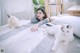 A woman laying on a bed with two white cats.