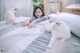 A woman laying on a bed with two white cats.