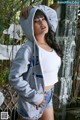 A woman in a gray hoodie and denim shorts posing for a picture.