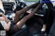 A woman sitting in the driver's seat of a car with her legs up.