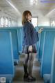 A woman in a school uniform standing on a train.