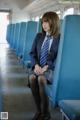 A woman in a school uniform sitting on a train.