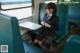 A woman in a school uniform sitting on a train.