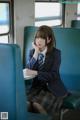 A woman in a school uniform sitting on a train.